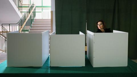 In einem leicht abgedunkelten Raum sind drei Wahlkabinen zu sehen, in der rechten gibt die polnische Parlamentssprecherin Malgorzata Kidawa-Blonska ihre Stimme ab.