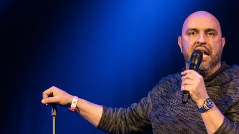 Der Kabarettist Serdar Somuncu steht auf einer dunklen Bühne