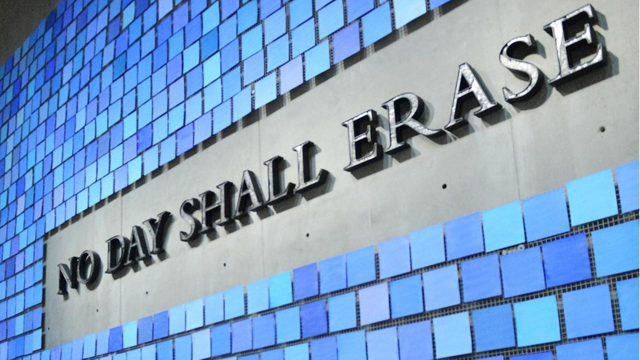 Eine Wand mit blauen Kacheln und dem Spruch "No day shall erase" erinnert im Nine-Eleven-Museum in New York an die Opfer der Terroranschläge vom 11. September 2001.
