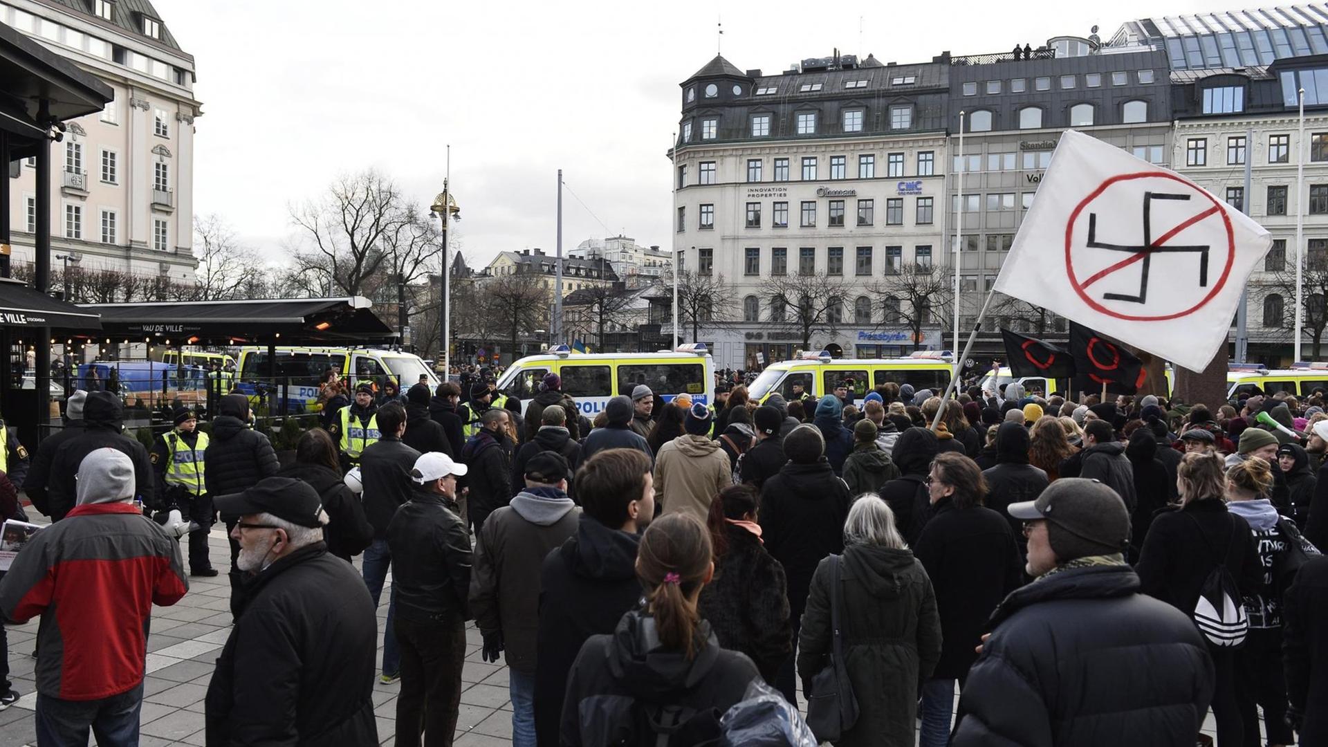Auf einem Platz in Stockholm demonstrieren Menschen gegen Rassismus und Fremdenfeindlichkeit. Ein Banner mit einem durchgestrichenen Hakenkreuz wird hochgehalten.