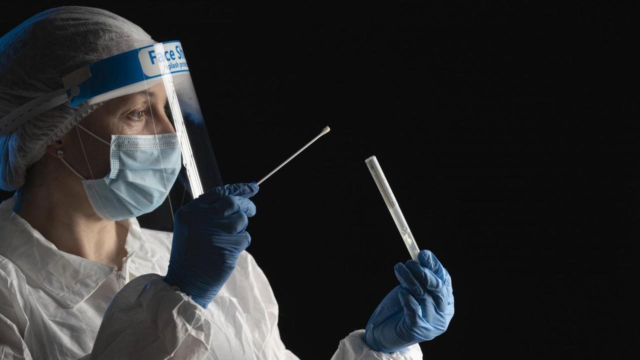 Woman in protective wear putting a swab into a tube model released Symbolfoto property released SNF00064