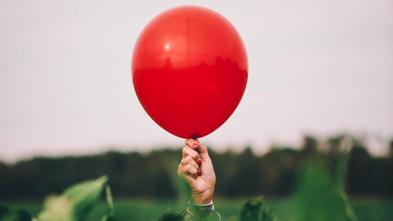 Eine Hand hält einen roten Ballon