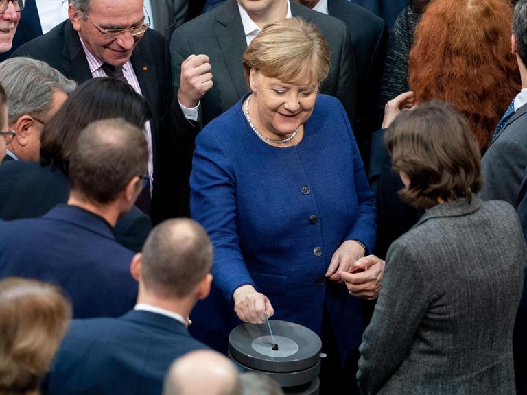 Bundeskanzlerin Angela Merkel (CDU, M) gibt bei der Sitzung des Bundestages ihre Stimmkarte bei der namentlichen Abstimmung über neue Organspende-Regeln ab.