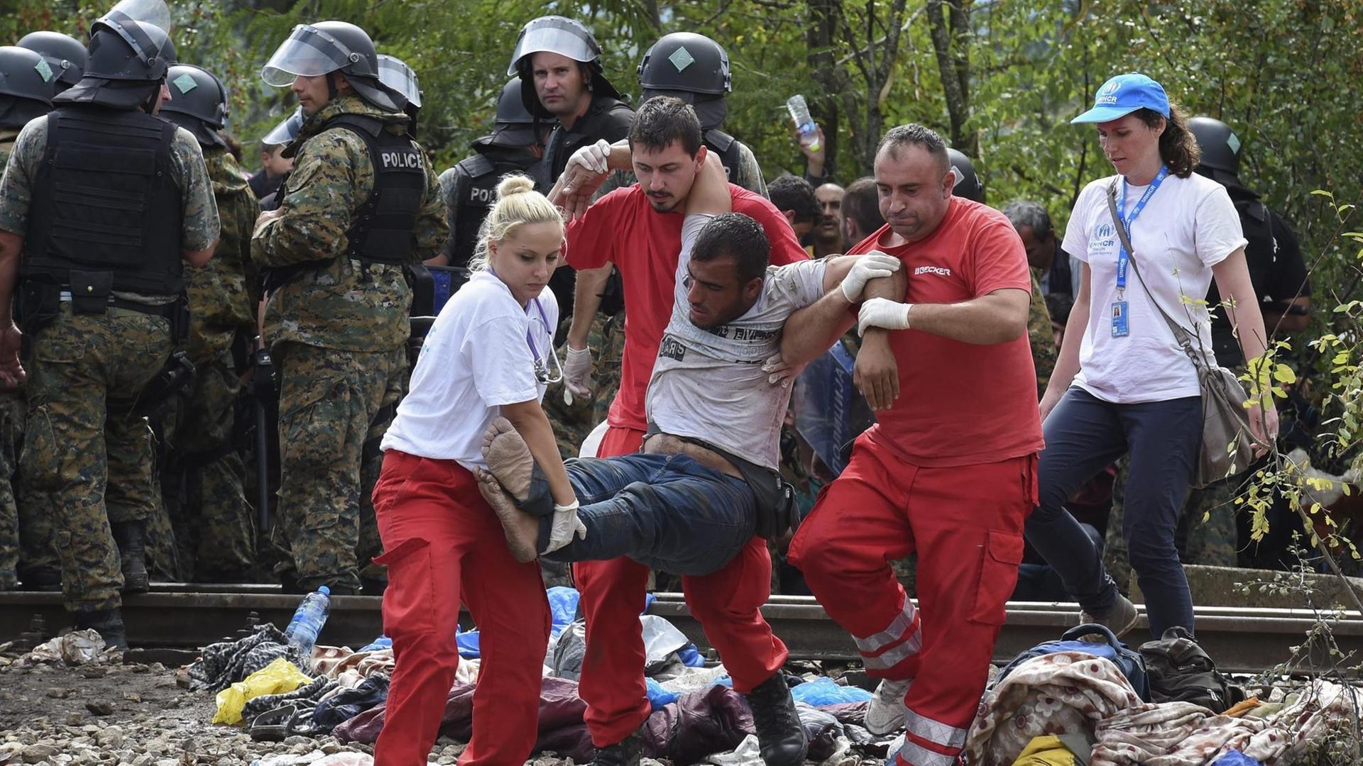 Sanitäter helfen einem kollabierten Mann an der Grenze zu Mazedonien.