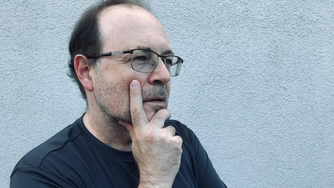 Der Komponist Jörg Mainka mit verschränkten Armen mit einer Hand im Gesicht