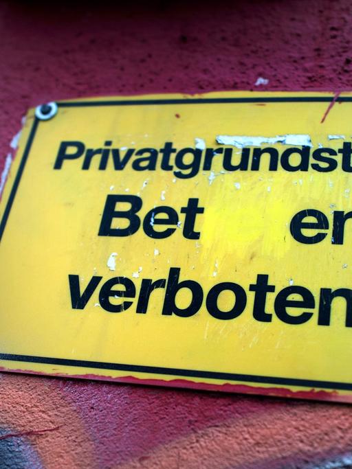 "Privatgrundstück - Beten verboten" steht auf einem Schild an einer Garagenwand in Dresden (Sachsen).
