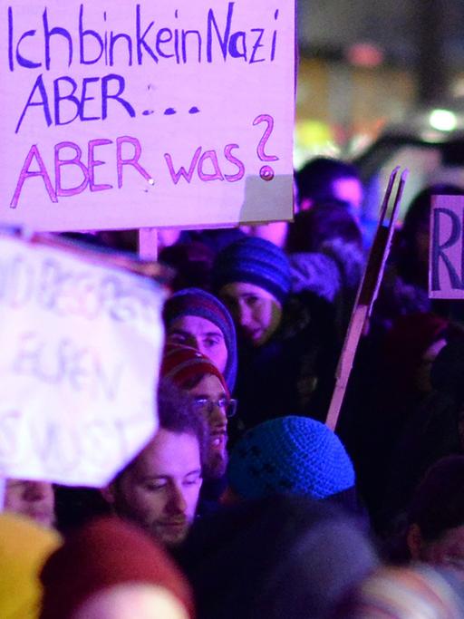 Demonstranten der Gegendemonstration zur "Pegida"-Kundgebung halten in Dresden Plakate hoch.