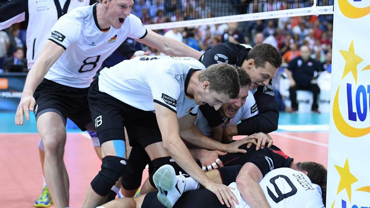 Die deutschen Volleyball-Herren stehen und liegen auf dem Spielfeld und feiern ihren Sieg gegen die serbische Mannschaft bei der EM 2017 in Polen.