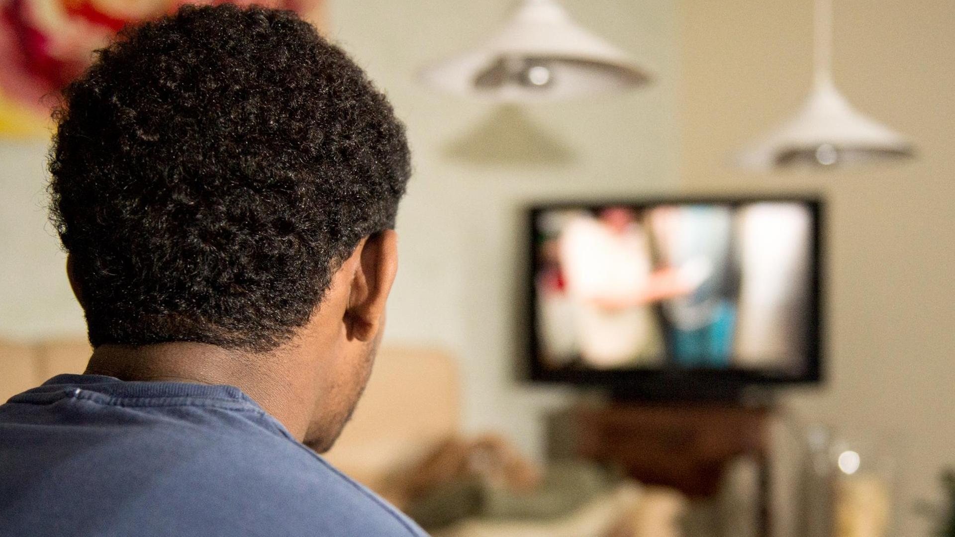 Ein junger Flüchtling schaut Fernsehen: eine deutsche Familie hat ihn aufgenommen.
