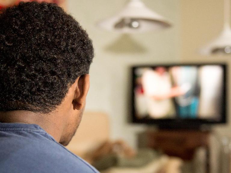 Ein junger Flüchtling schaut Fernsehen: eine deutsche Familie hat ihn aufgenommen.