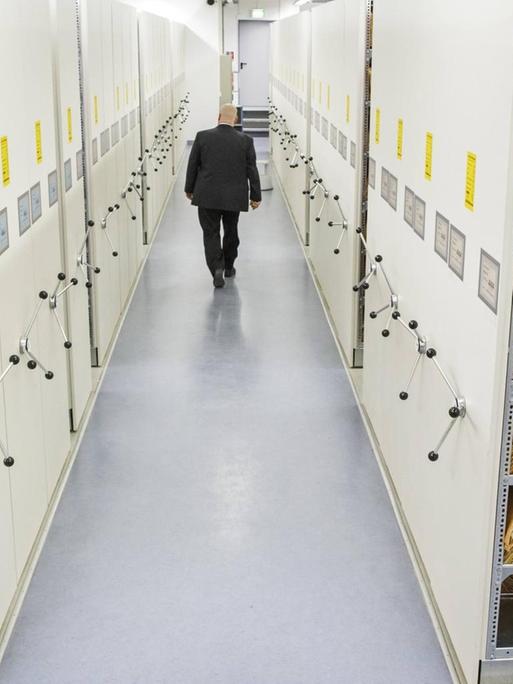Ein Mitarbeiter im Archiv der Stasi-Unterlagenbehörde in Berlin-Lichtenberg geht einen Gang mit Akten entlang.
