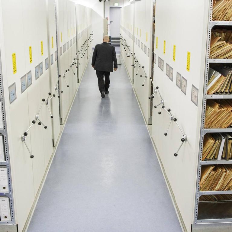 Ein Mitarbeiter im Archiv der Stasi-Unterlagenbehörde in Berlin-Lichtenberg geht einen Gang mit Akten entlang.