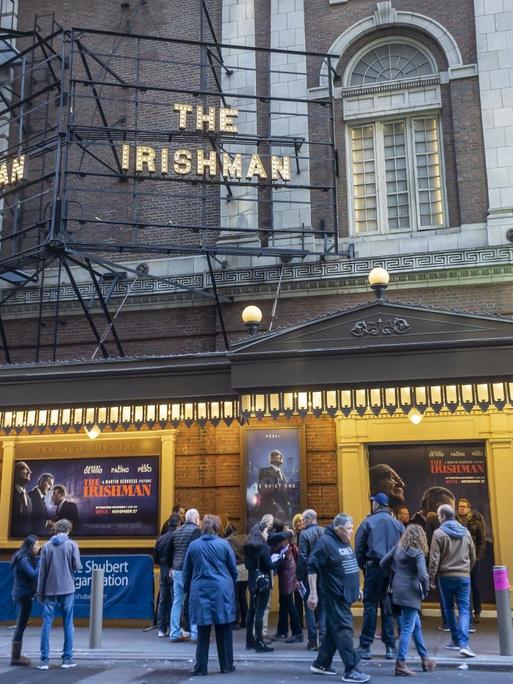Aussenansicht des Belasco Theatres in New York, in dem die Netflix-Produktion "The Irishman" von Martin Scorsese gezeigt wurde, bevor der dann auf der Stremingplatform selber lieft. An dem alten Gebäude steht oben "The Irshman" in Leuchtschrift. Auf der Strasse vor dem Theater steht eine Gruppe von Leuten und man sieht die Plakate des Film.