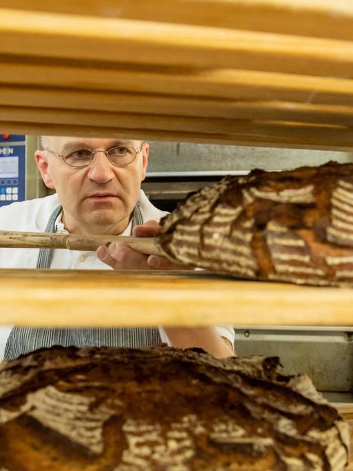 Bäcker Arnd Erbel legt ein Brot in ein Regal.