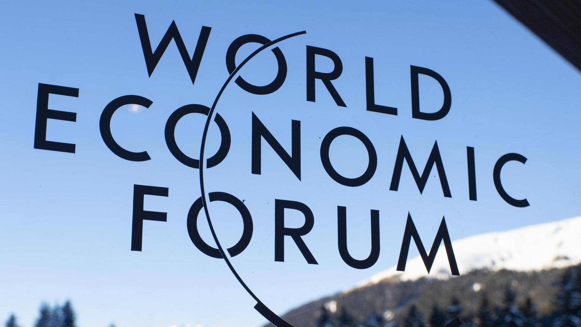 Logo des Weltwirtschaftsforums in Davos vor einer verschneiten Berglandschaft.