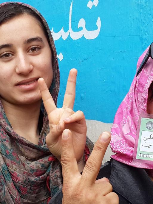 Frauen, die 2014 bei der Präsidentschaftswahl in Afghanistan ihre Stimme abgeben. Unter Taliban-Herrschaft undenkbar. Sie zeigen das Victory-Zeichen.