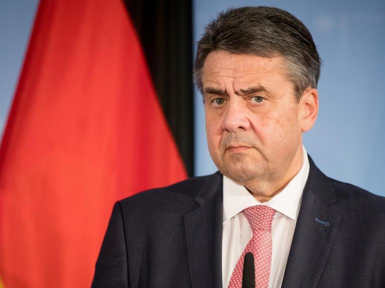 Sigmar Gabriel (SPD) steht vor einer Deutschland-Flagge und schaut skeptisch bis grimmig.