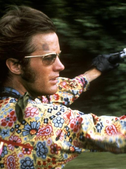 Peter Fonda mit buntem Blumenhemd und wehendem Haar in voller Fahrt auf seinem Motorrad im Film Easy Rider.
