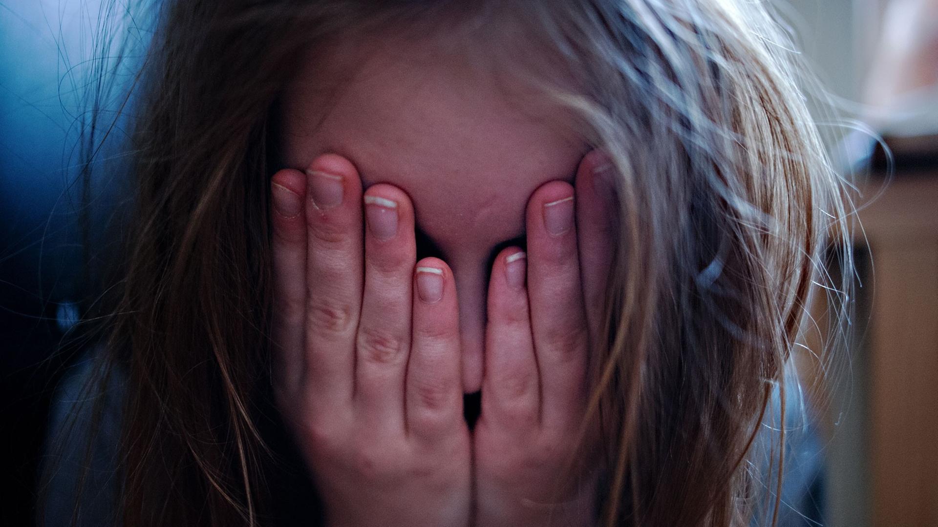 ILLUSTRATION - Ein junges Mädchen hält sich am 24.01.2014 in Berlin die Hände vor ihr Gesicht