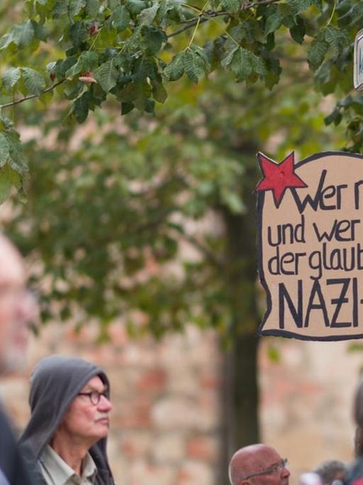 Ein Schild hängt während der Kundgebung der Chemnitzer Friedensgruppen am Roten Turm an einem Straßenschild. Darauf steht: Wer nichts denkt und nichts weiß. der glaubt den ganzen Nazi-Scheiß.