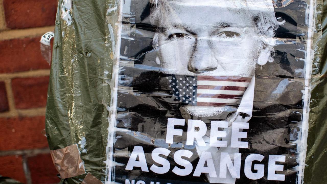 Plakat mit einem Porträt von Julian Assange mit der amerikanischen Fahne als Knebel über seinem Mund.