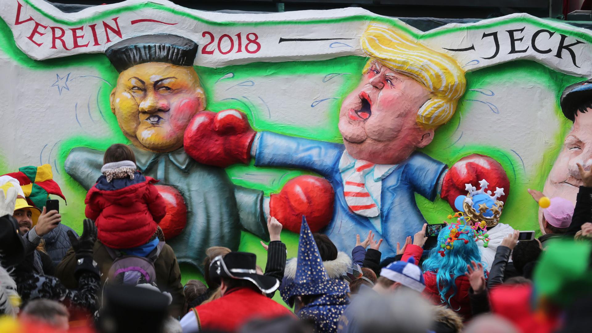 Rosenmontagsumzug in Düsseldorf: Ein politischer Mottowagen zeigt den US-Präsidenten Donald Trump (r) und Kim Jong Un, Machthaber von Nordkorea, bei einem Boxkampf.