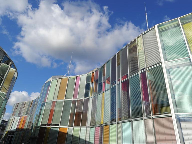 Das Zentrum für Photonik und Optische Technologien im Technologiepark Berlin-Adlershof. Ein Glasbau mit gebäudehohen Jalousetten, die mit ihren verschiedenen Farben den Wechsel von Tag und Nacht symbolisieren.
