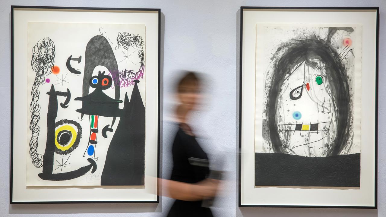 Eine Besucherin wandelt zwischen zwei Miró-Gemälden in einer Ausstellung.