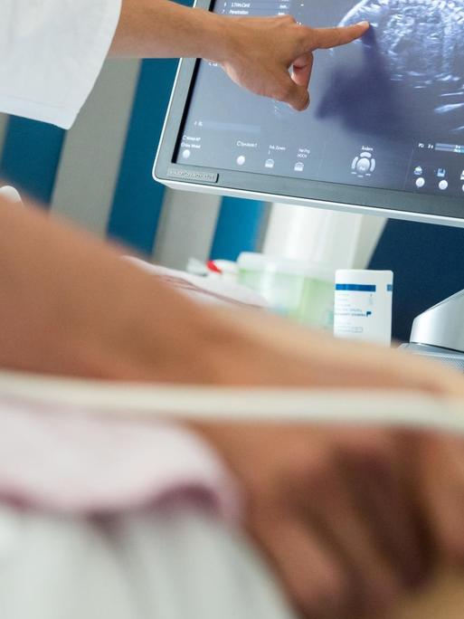Ein Arzt untersucht den Bauch von einer Frau mit einem Ultraschall-Gerät