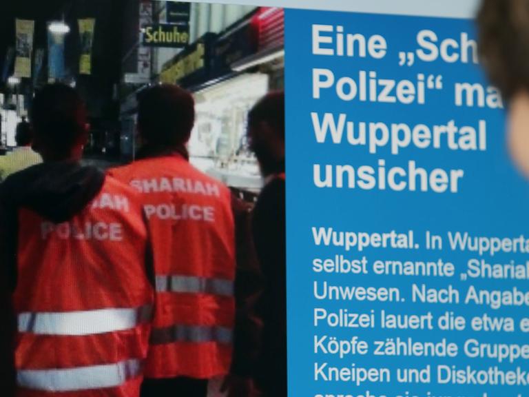 Ein Mann blickt auf einen Computer-Bildschirm, auf dem selbsternannte "Scharia-Polizisten" zu sehen sind.