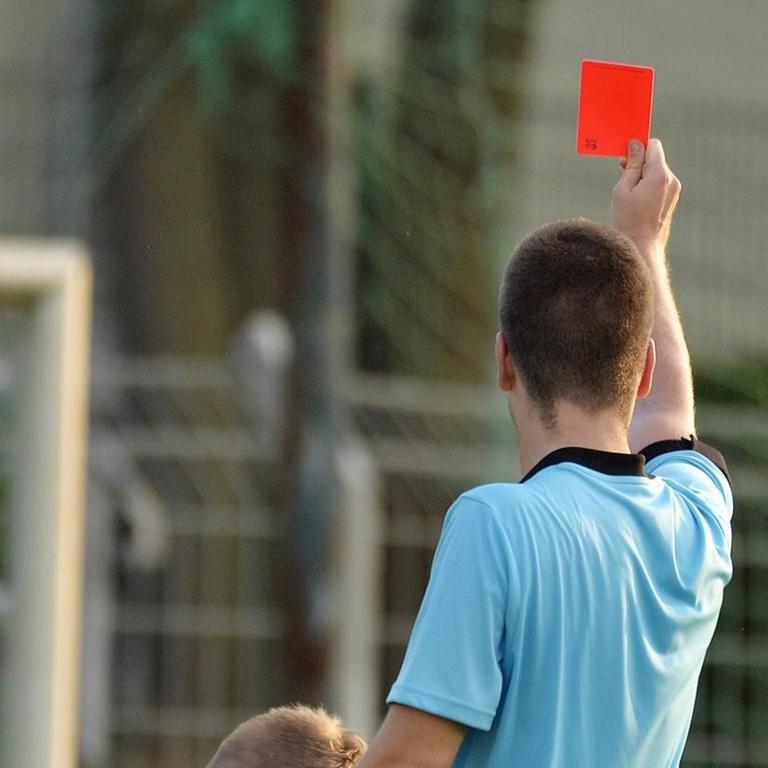 Ein Schiedsrichter zeigt eine rote Karte.