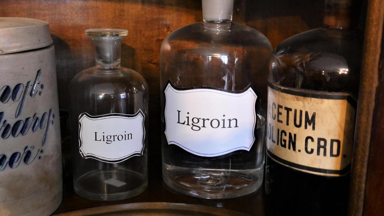 In einer Apotheke stehen braune Arzneiflaschen, eine mit der Aufschrift "Ligroin".