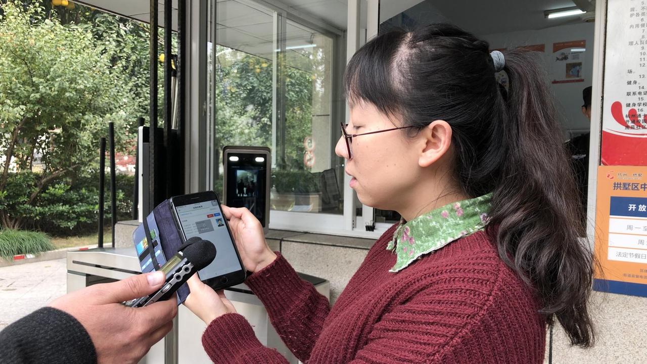 Lehrerin Zhu Zhiyao von einer Schule in Hangzhou sieht auf dem Smartphone, wer zu spät kommt.