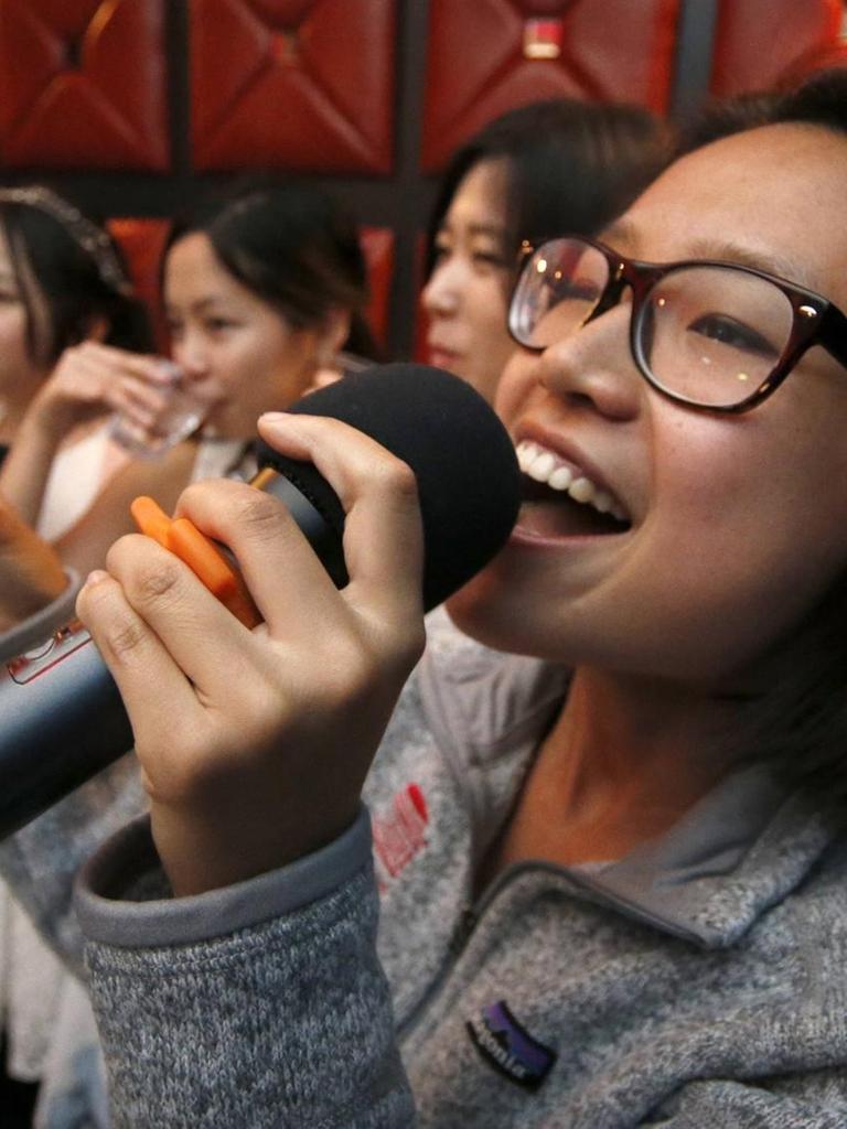 Eine Frau singt mit weiteren Gästen in einer Karaoke-Bar