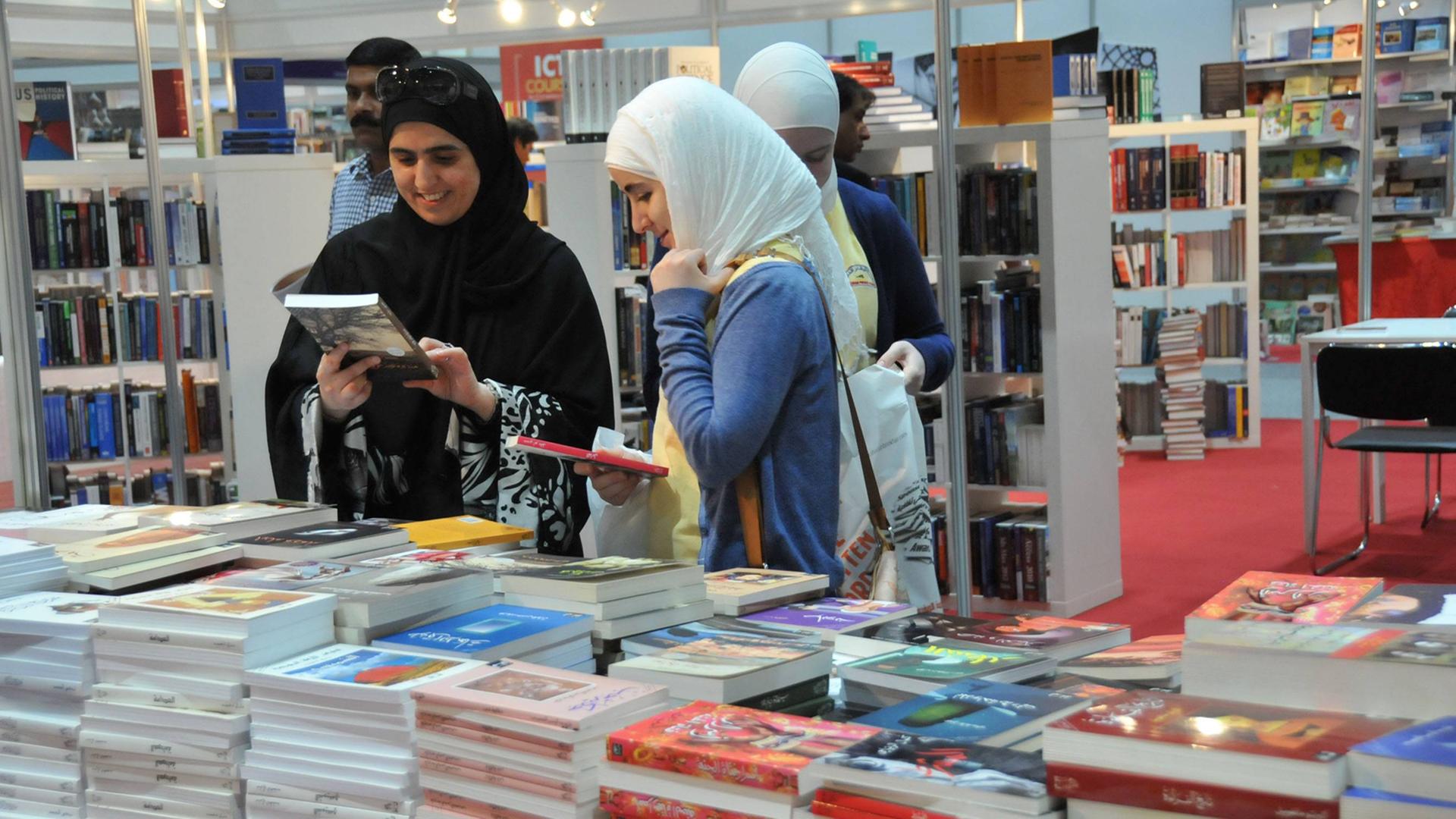 Auf der internationalen Buchmesse in Abu Dhabi gucken sich zwei Frauen Bücher an.