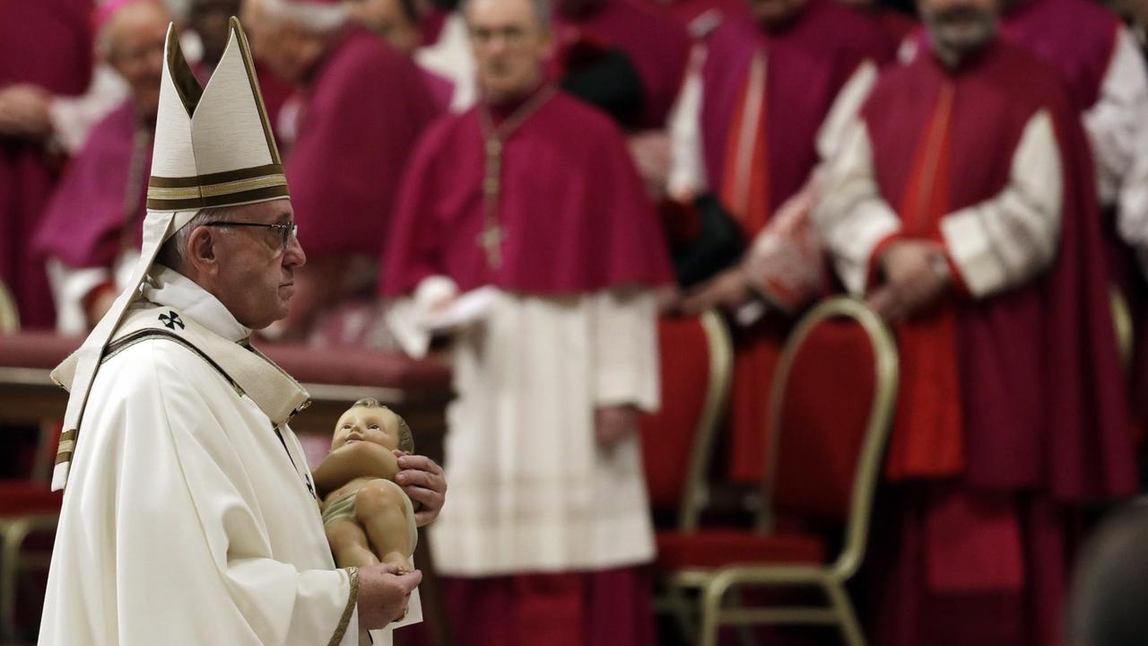 Papst Franziskus hält während der Heiligabend-Messe im Petersdom eine Figur des Jesuskindes.