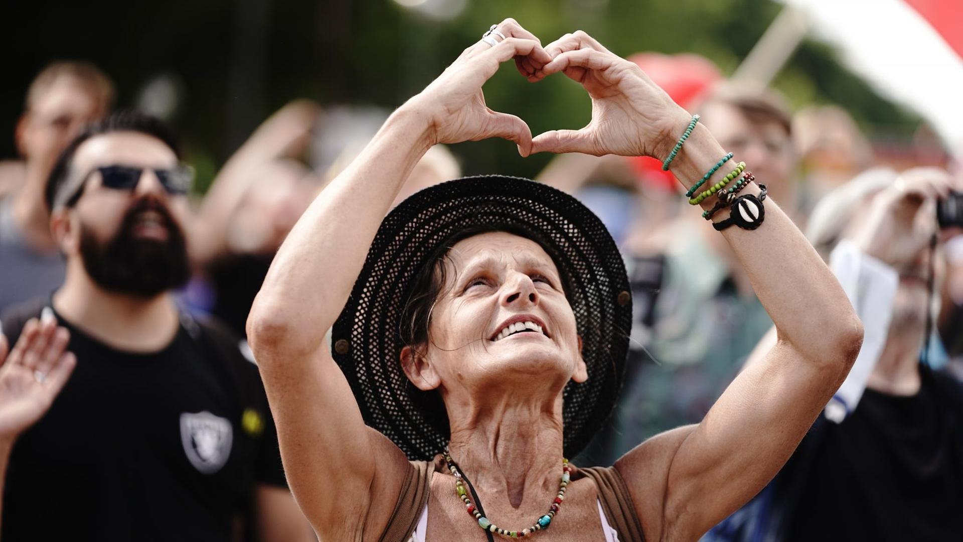 Eine Teilnehmerin formt ein Herz mit den Händen bei einer Demonstration gegen die Corona-Maßnahmen.