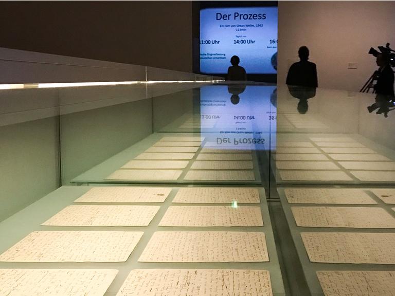 Originale Schriftstücke des Schriftstellers Franz Kafka liegen am 28.06.2017 in Berlin in einer Vitrine aus. Zu sehen ist der Fussboden der Ausstellung mit einer Leuchttafel im Hintergrund. Die Ausstellung "Franz Kafka. Der ganze Prozess" ist vom 30. Juni bis 28. August 2017 im Martin-Gropius-Bau in Berlin zu sehen. Foto: Sophia Kembowski/dpa