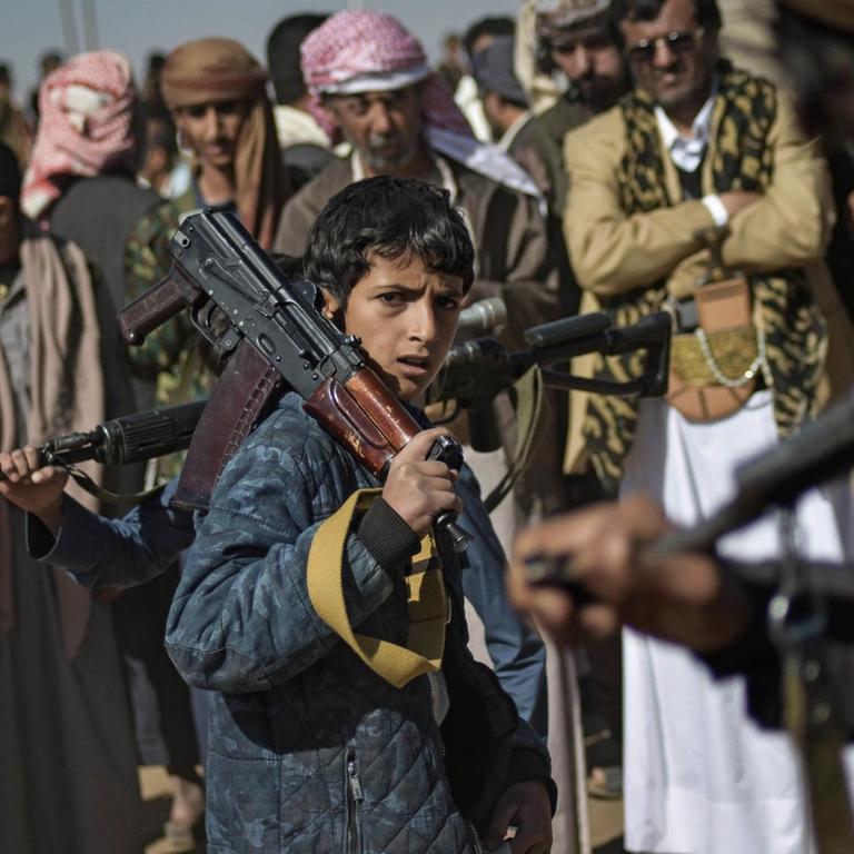Ein Junge trägt auf einer Rekrutierungsversammlung für neue Kämpfer der Huthi-Rebellen in Sanaa (Jemen) ein Gewehr über der Schulter. 