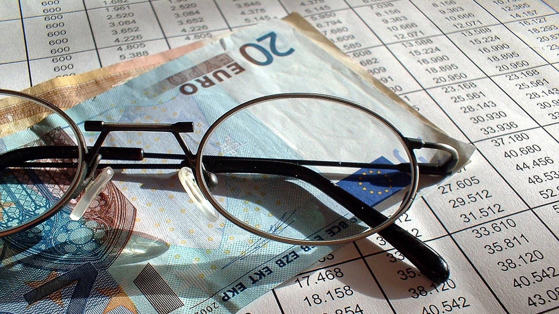 Brille, 20 Euro Schein und die Auflistung der Rückkaufswerte und Guthaben einer Lebensversicherung (Symbolbild)