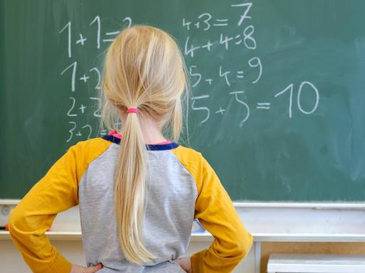 Ein Schulkind steht nachdenklich vor Gleichungen an einer Schultafel in Dresden