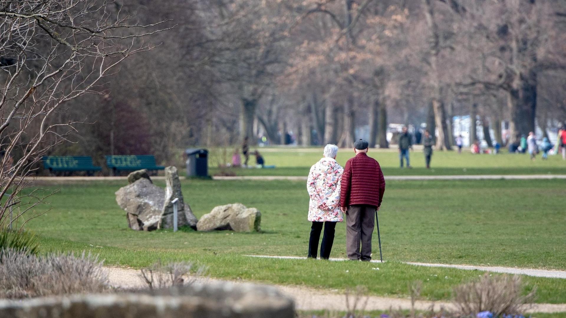 Ein Rentnerpaar geht in einem Park spazieren.