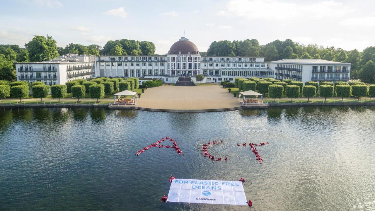Greenpeace-Aktivisten schwimmen in Bremen vor dem Parkhotel im Hollersee und zeigen dabei ein Transparent mit dem Schriftzug "For Plastic Free Oceans" (Für plastikfreie Ozeane)