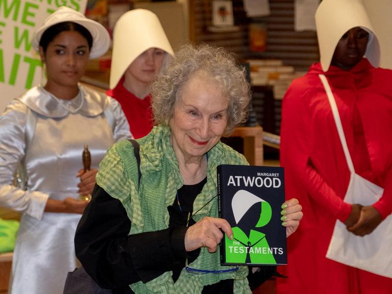 Margaret Atwood posiert mit ihrem neuen Roman "Die Zeuginnen" und als Figuren aus dem Roman verkleideten Schauspielerinnen bei einer Lesung in einem Londoner Buchladen.