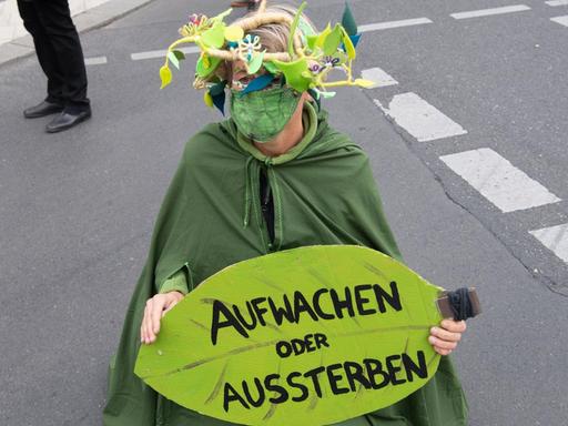 Eine Umweltaktivistin hält während einer Demonstration unter dem Motto «Trauerzug der toten Bäume» von Extinction Rebellion (XR) unweit des Bundeslandwirtschaftsministeriums ein Schild mit der Aufschrift «Aufwachen statt Aussterben». Für diese Woche hat Extinction Rebellion Protestaktionen gegen Umweltzerstörung und Klimawandel angekündigt.