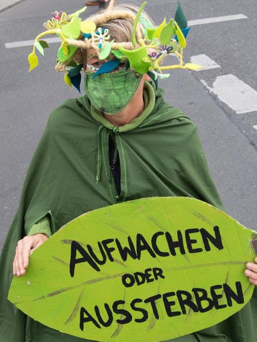 Eine Umweltaktivistin hält während einer Demonstration unter dem Motto «Trauerzug der toten Bäume» von Extinction Rebellion (XR) unweit des Bundeslandwirtschaftsministeriums ein Schild mit der Aufschrift «Aufwachen statt Aussterben». Für diese Woche hat Extinction Rebellion Protestaktionen gegen Umweltzerstörung und Klimawandel angekündigt.