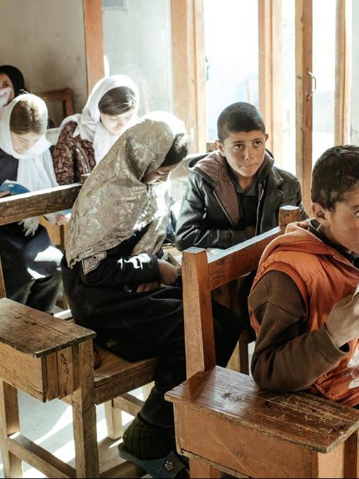 Schule in Afghanistan: Ein Mädchen und ein Junge lesen gemeinsam aus einem Heft.