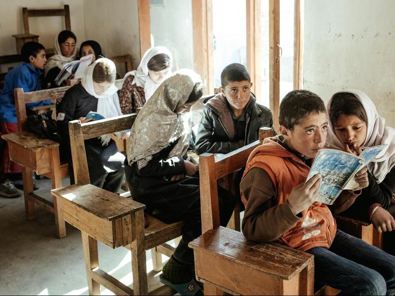 Schule in Afghanistan: Ein Mädchen und ein Junge lesen gemeinsam aus einem Heft.