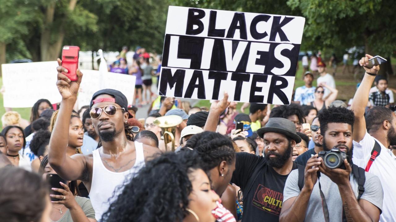 Mann hält bei Demonstration ein Schild hoch: "Black Lives Matter"