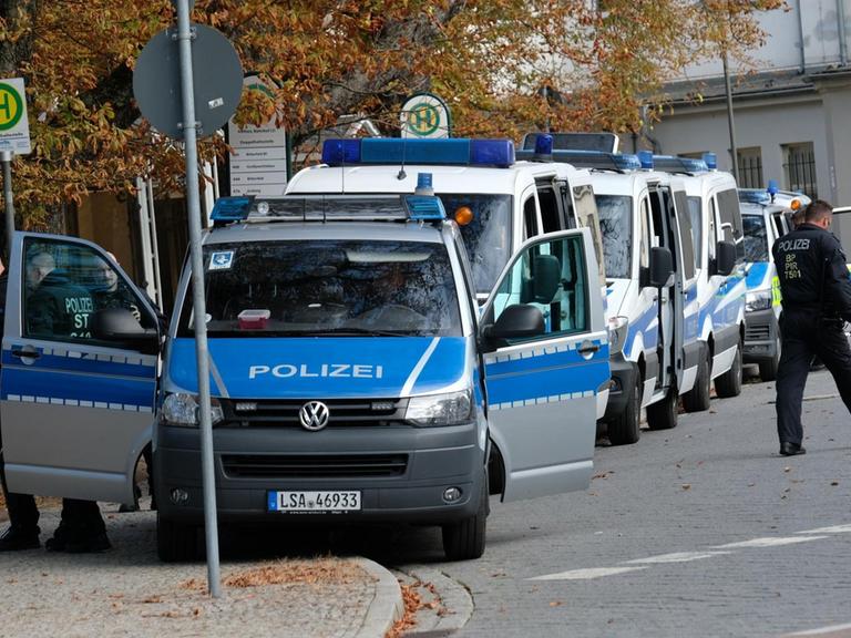 Polizisten stehen mit ihren Fahrzeugen am Bahnhof von Köthen